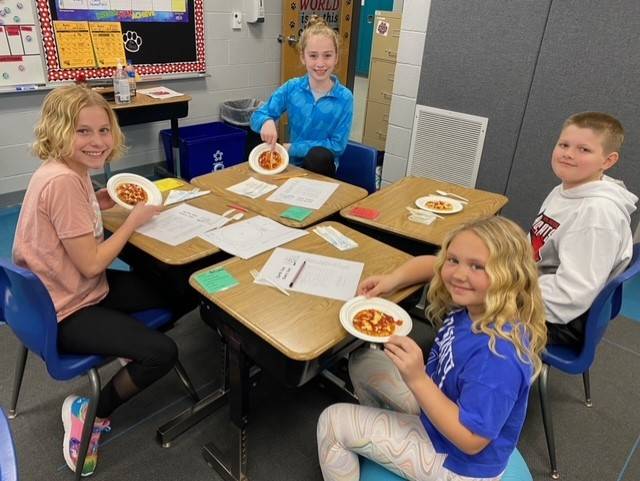 4th grade students eating pizzas made during service day