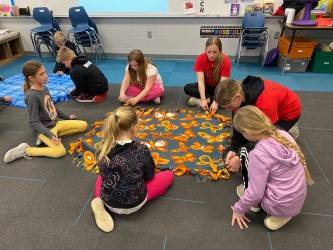 3rd grade students making tie blankets for service day